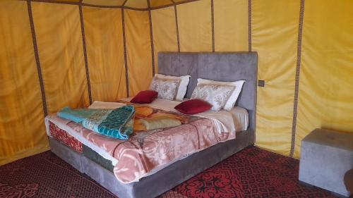 a bed in a tent with pillows on it at camp erg znaigui in Taouz