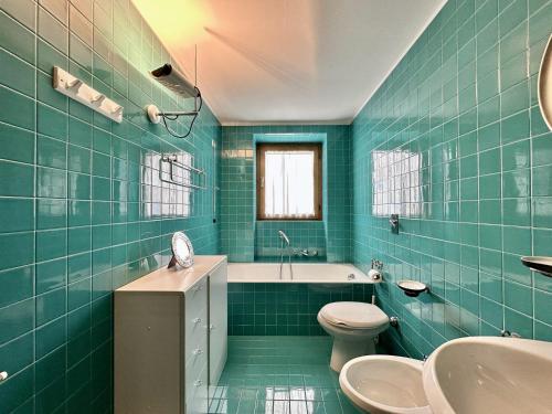 a green tiled bathroom with a toilet and a sink at Classy 4 bedroom few steps from centre in Cortina dʼAmpezzo