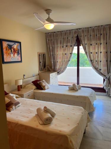 a bedroom with two beds and a large window at Apartamentos Parque Botanico in Estepona