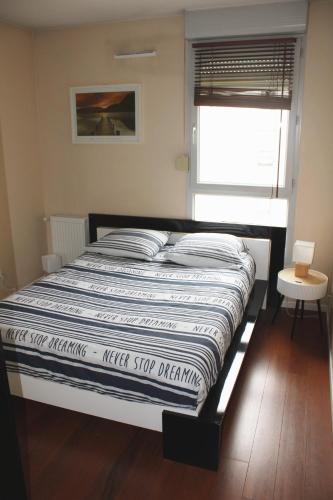 - un lit avec une couette rayée dans une chambre dans l'établissement Cosy Appart - Clim - Balcon - Parking - Spacieux T2 - Proche Eurexpo Stade, à Saint-Priest
