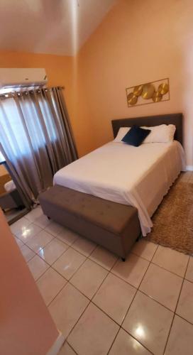 een slaapkamer met een bed en een raam bij Caribbean Estate Vacay Stay 3 in Portmore