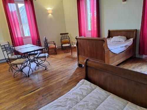 une chambre avec deux lits, une table et des chaises dans l'établissement Les Chambres du Cheval Blanc, à Allassac