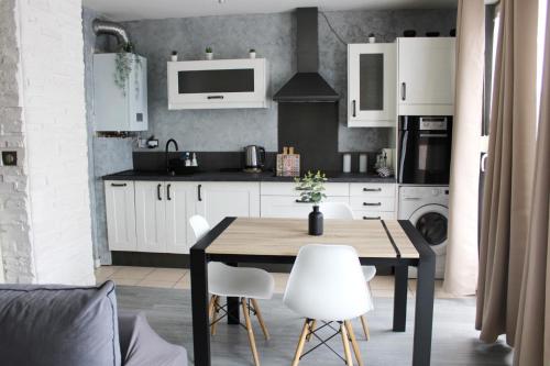 una cucina con un tavolo in legno e mobili bianchi di Cosy Appart - Clim - Balcon - Parking - Spacieux T2 - Proche Eurexpo Stade a Saint-Priest