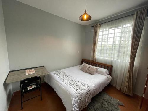 a bedroom with a bed with a table and a window at Jojo's Homestay - Bomet Town in Bomet