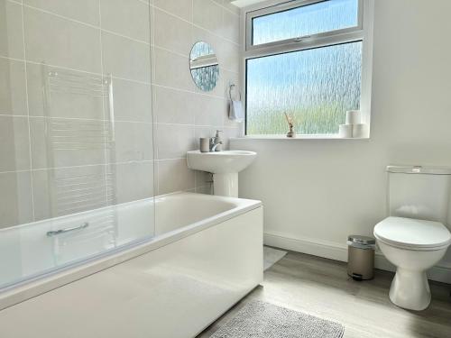 a white bathroom with a toilet and a sink at 3 Bed Entire House with WIFI, Parking and Garden Space in Enfield in Enfield Lock