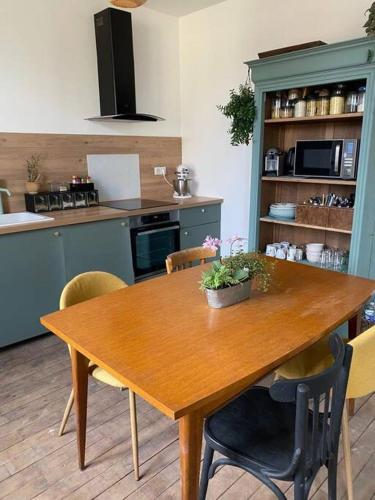 - une table en bois dans une cuisine avec des chaises et une table dans l'établissement La maison des voyageurs avec grand parking privé -calme et sérénité, à Chevincourt