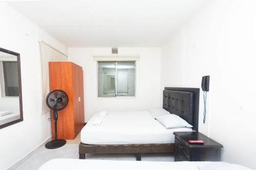 a small bedroom with a bed and a window at Hotel Villa Real in Medellín