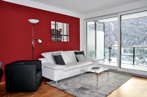een woonkamer met een witte bank en rode muren bij Chasa Miramunt 4 in Scuol