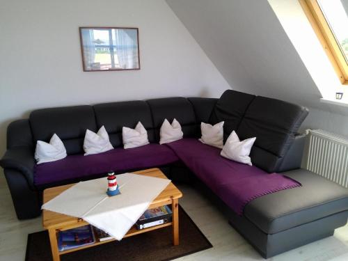 a living room with a black couch and a table at Moderne Ferienwohnung mit Balkon in Strandnähe in Friedrichskoog