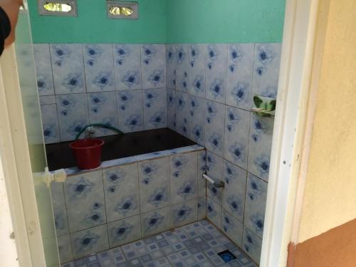 Baño con azulejos azules y blancos en la pared en Homestay Desa Wisata Silokek, en Duriangadang