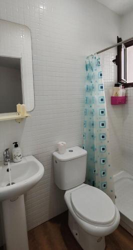 a white bathroom with a toilet and a sink at Apartamento Karmo in Carmona