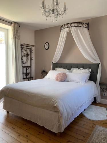 ein Schlafzimmer mit einem großen weißen Bett mit Baldachin in der Unterkunft The Cool Lounge à Coulonges - Charente in Coulonges