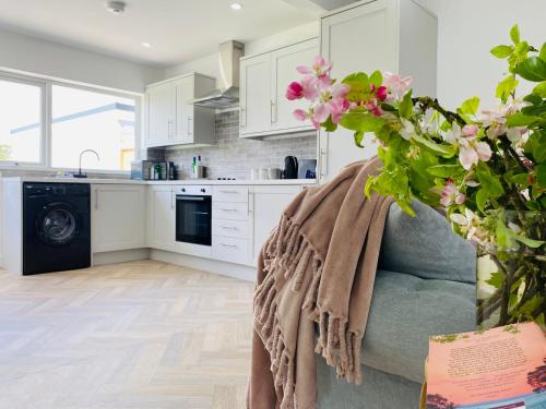 a kitchen with white cabinets and a couch with a blanket at Blossom Lodge - Detached bungalow near Kings Lynn in Narborough