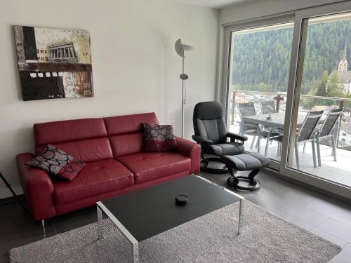 ein Wohnzimmer mit einem roten Sofa, einem Tisch und Stühlen in der Unterkunft Chasa Miramunt 2 in Scuol