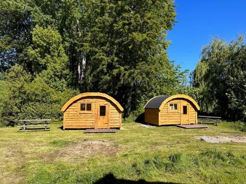 two wooden shelters in a field with a bench at Camping & Pension Au an der Donau in Au an der Donau