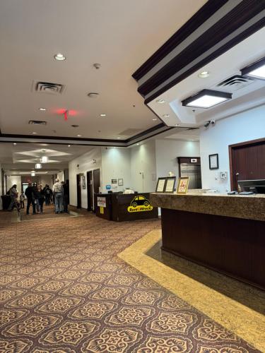 a hotel lobby with a reception desk and people walking at Divya Sutra Plaza and Conference Centre Calgary Airport in Calgary