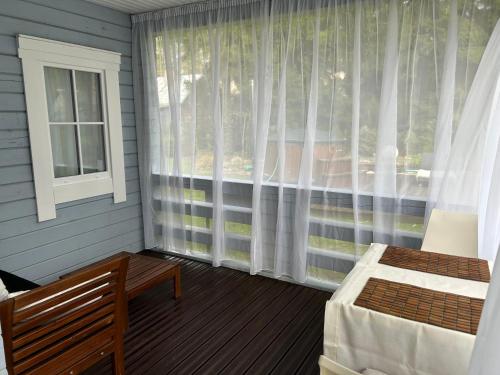 a bedroom with a window with curtains and a bed at Romantic cozy house Kirzacinas pirts with sauna close to seaside in Skulte