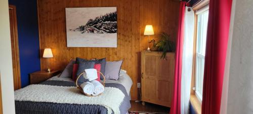 1 dormitorio con 1 cama y pared de madera en Gîte Aux Jardins De L'Anse, en Percé