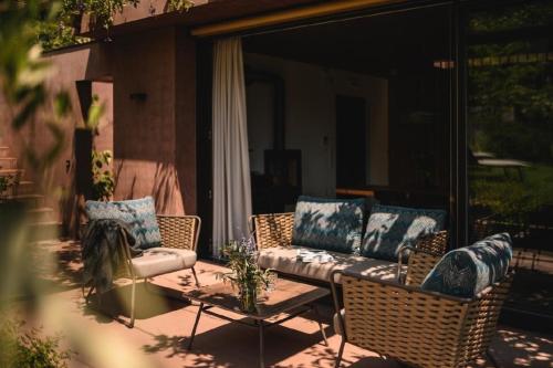 un patio con sillas de mimbre y un sofá en un porche en Villa mit Pool, Whirlpool, Sauna und großem Privatgarten, en Caldaro