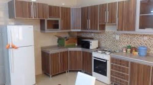 uma cozinha com armários de madeira e um frigorífico branco em Jordan road Guest House em Madaba