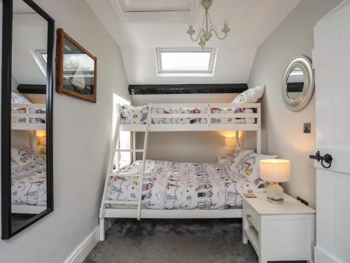 a bedroom with two bunk beds and a mirror at Tan Yr Allt in Pwllheli