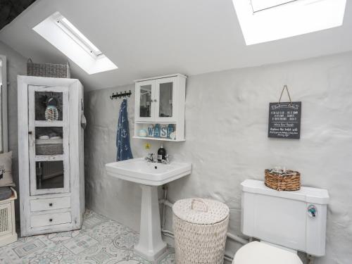 a white bathroom with a sink and a toilet at Tan Yr Allt in Pwllheli