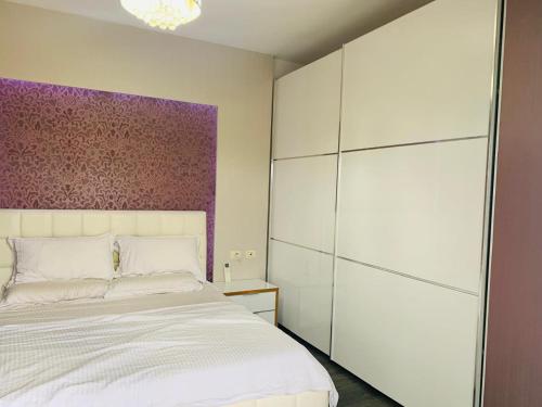 シュコダルにあるLika's Apartment 1の紫の壁のベッドルーム1室(白いベッド1台付)