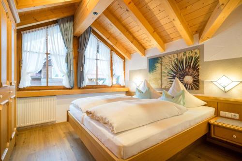 ein Schlafzimmer mit einem großen Bett in einem Zimmer mit Fenstern in der Unterkunft Landhaus Barbara Ferienwohnungen in Oberstdorf
