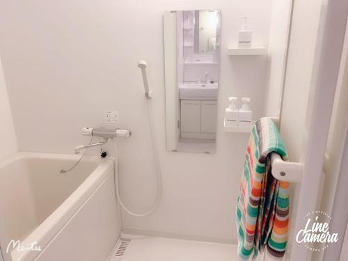 baño blanco con ducha y lavamanos en Ikebukuro 2bedroom 704 en Tokio