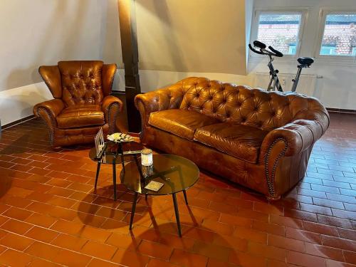 ein Wohnzimmer mit einem Ledersofa und 2 Stühlen in der Unterkunft Luxurious loft on 2 floors in Köln