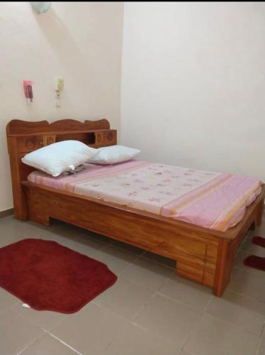 - un lit en bois dans une chambre dotée d'un tapis rouge dans l'établissement Studio meublé, à Abomey-Calavi