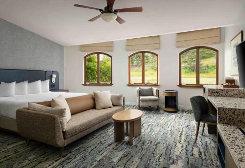 a living room with a couch and a bed and windows at El Colibri Hotel & Spa in Cambria