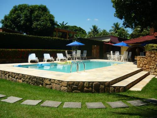uma piscina com cadeiras e guarda-sóis num quintal em Sitio do Popay no Rio de Janeiro