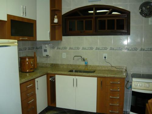 uma cozinha com armários brancos e um lavatório em Sitio do Popay no Rio de Janeiro
