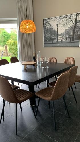 a dining room table with chairs and a lamp at Villa Riverside met hottub, eigen aanlegsteiger, zwemtrap, trampoline en kano's in Zeewolde
