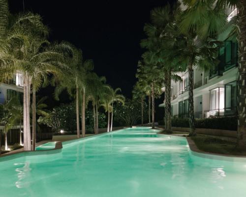a swimming pool with palm trees at night at La Vita Phuket Rawai in Rawai Beach