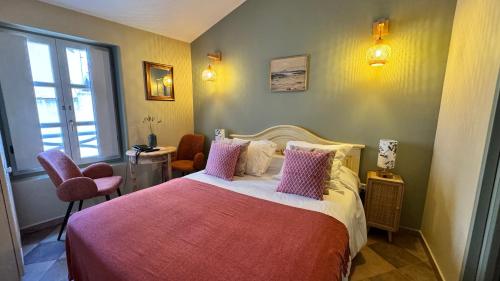 a bedroom with a large bed with pink pillows at COLOMBA Hôtel Restaurant in Bonifacio