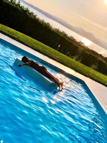 a person laying on a surfboard in a swimming pool at LHV Garda Lake - Private POOL and SPA in Bardolino