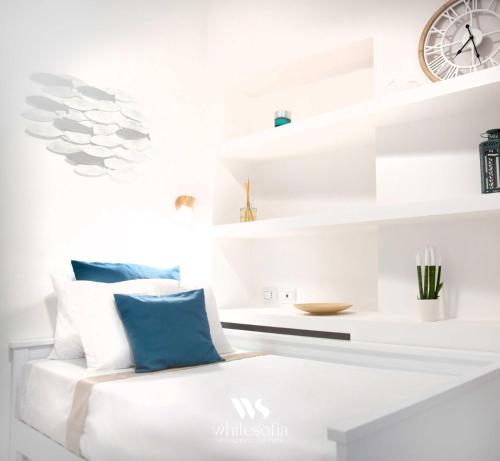 Habitación blanca con silla blanca y reloj en WHITE SOFIA - uno sguardo sul mare, en Bari