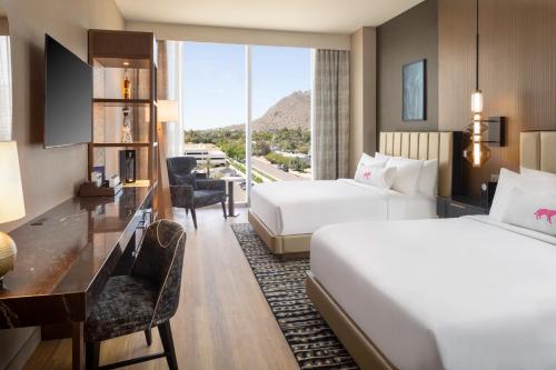 a hotel room with two beds and a desk at Caesars Republic Scottsdale, a Hilton Hotel in Scottsdale