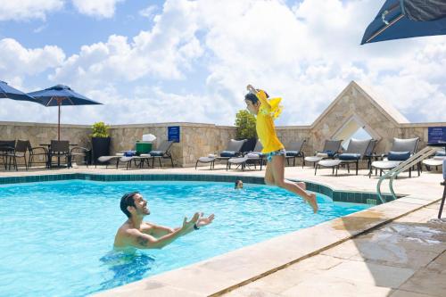 a man and a woman jumping in a swimming pool at Hotel Atlante Plaza in Recife