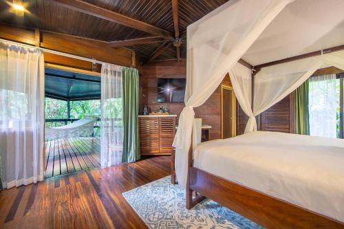 a bedroom with a canopy bed and a bathroom at Chachagua Rainforest Hotel & Hot Springs in Fortuna