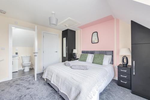 a bedroom with a large bed and a bathroom at 3 Bed House - Contractors, Relocators & Visitors, Coffee Machine & Free Parking - Sleeps 6 in Bedford