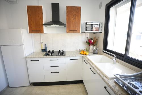 een keuken met witte kasten, een wastafel en een raam bij Un ton Violet in Sfax