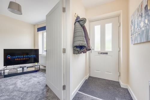 een hal met een witte deur en een televisie bij 3 Bed House - Contractors, Relocators & Visitors, Free Parking & Coffee Machine - Long stay rates in Bedford
