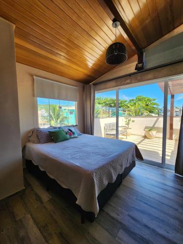 a bedroom with a bed and a large window at Casamar Lofts, Praia dos Anjos Arraial do Cabo in Arraial do Cabo