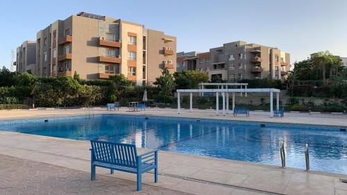 um banco azul sentado ao lado de uma piscina com edifícios em شقه فندقية للإيجار بالشيخ زايد em Sheikh Zayed