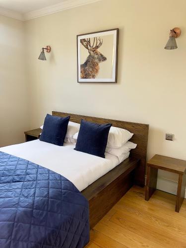 ein Schlafzimmer mit einem Bett mit blauen Kissen und einem Hirsch an der Wand in der Unterkunft Homely One Bedroom Apartment in London