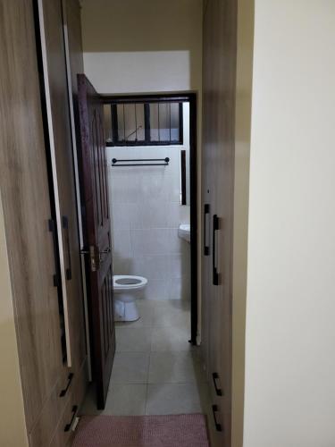La salle de bains est pourvue de toilettes, d'une fenêtre et d'une porte. dans l'établissement G&G Homes Executive Suite, à Nakuru