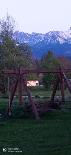 a wooden bridge in a field with mountains in the background at Pokoje ,,Goramiba''Jurgów in Jurgów